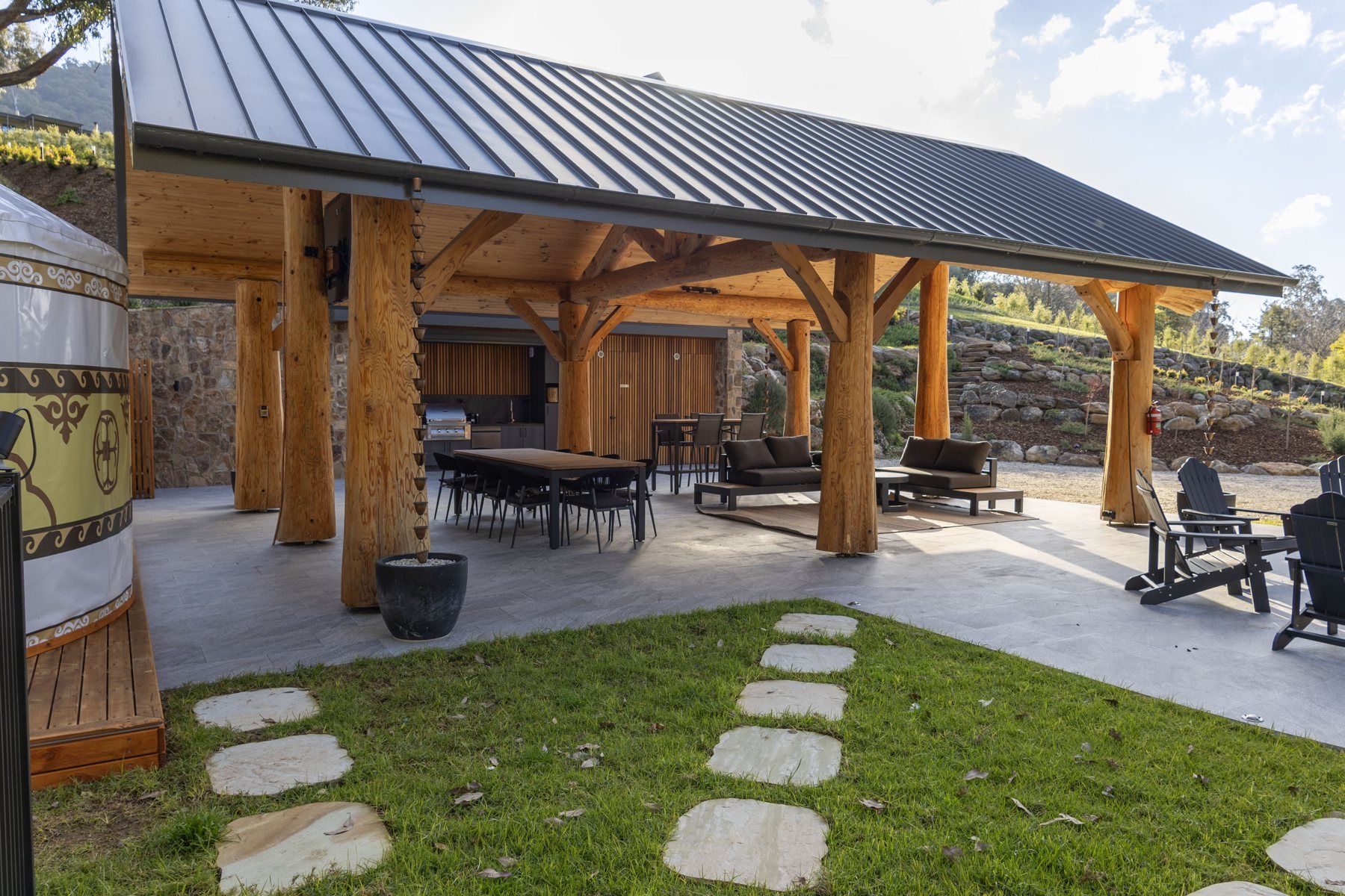 The log BBQ shelter with the dining table and lounge