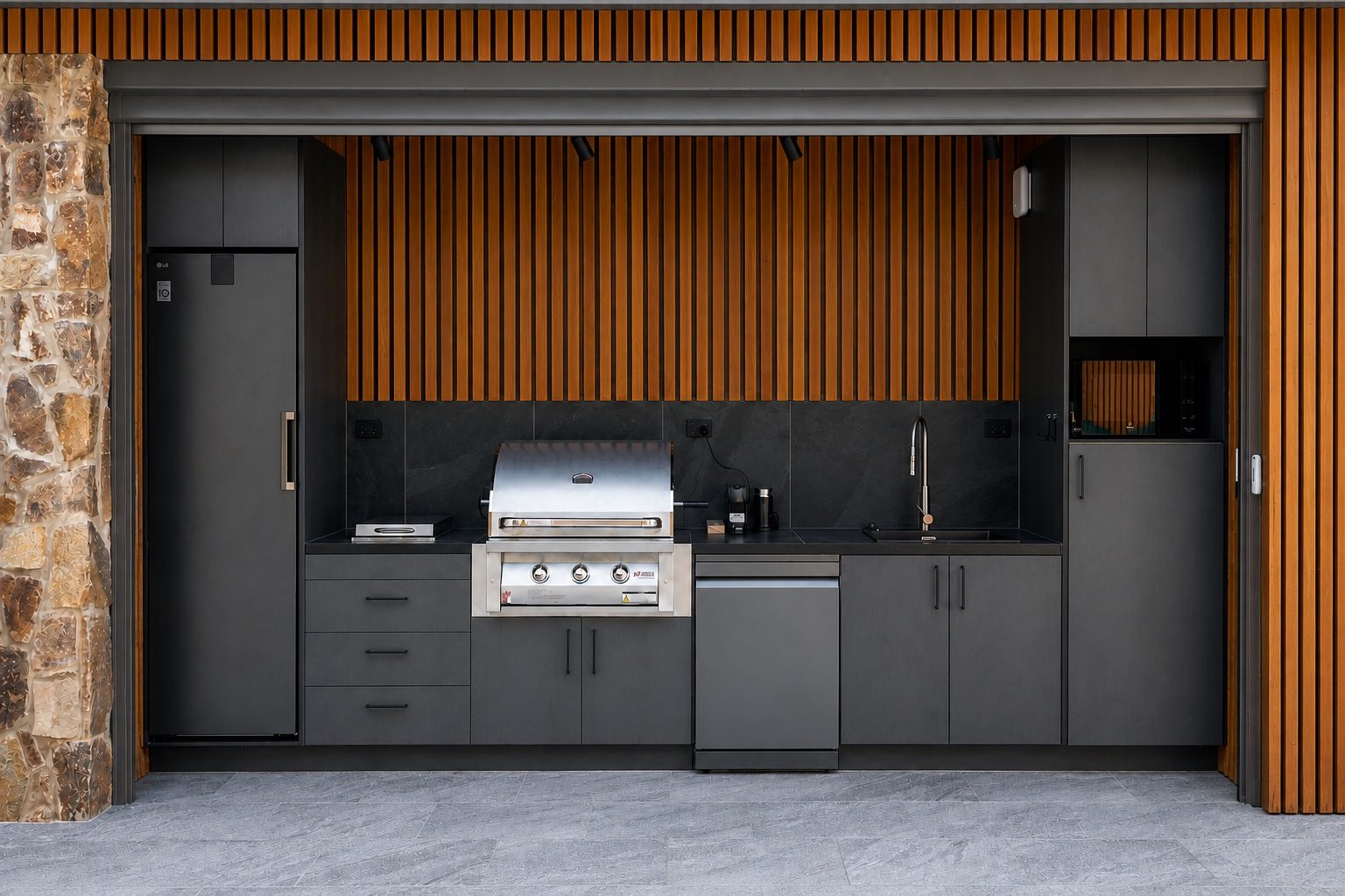 The outdoor kitchen: gas BBQ, cooktop, fridge and sink