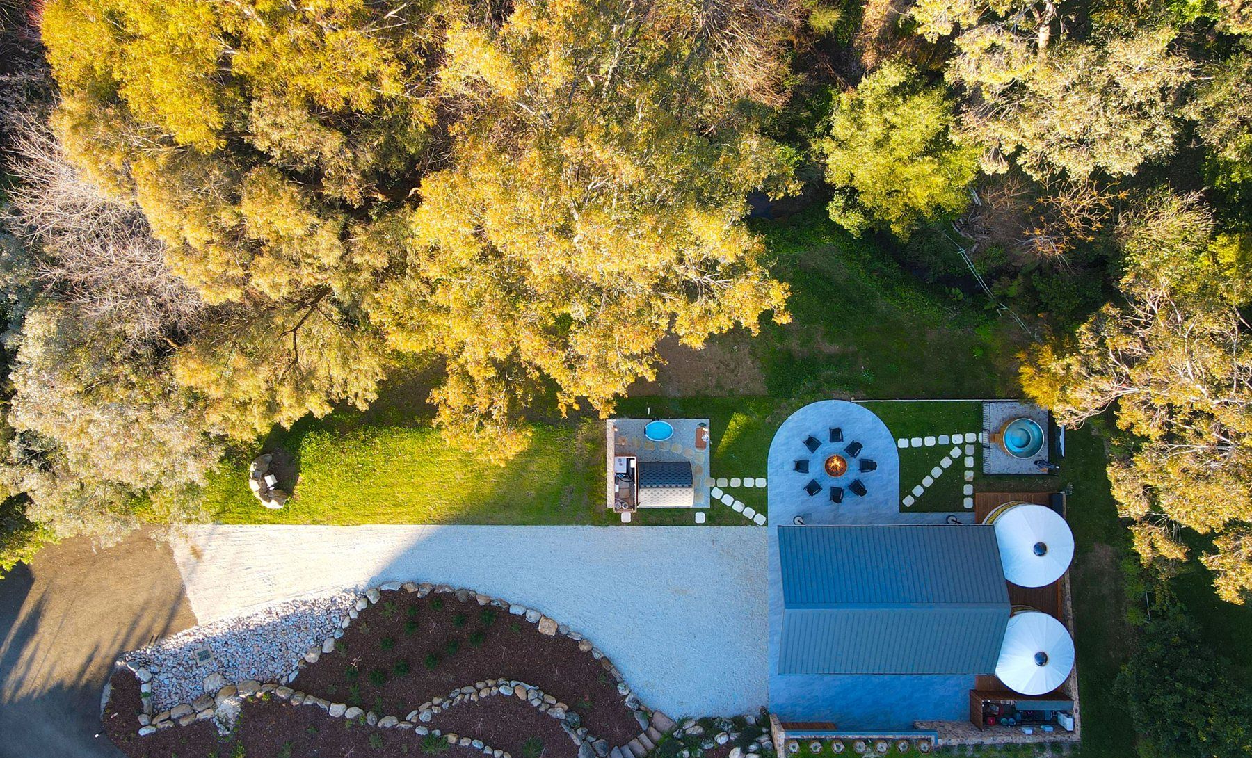 Bogong Nights glamping near Mount Beauty from above: two yurts, the firepit circle, the private sauna and the spa among the trees