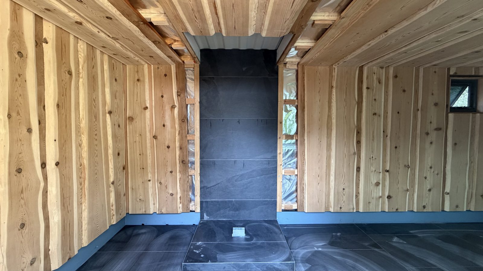 Inside the Bright banya: cedar lining and the slate wall behind the heater