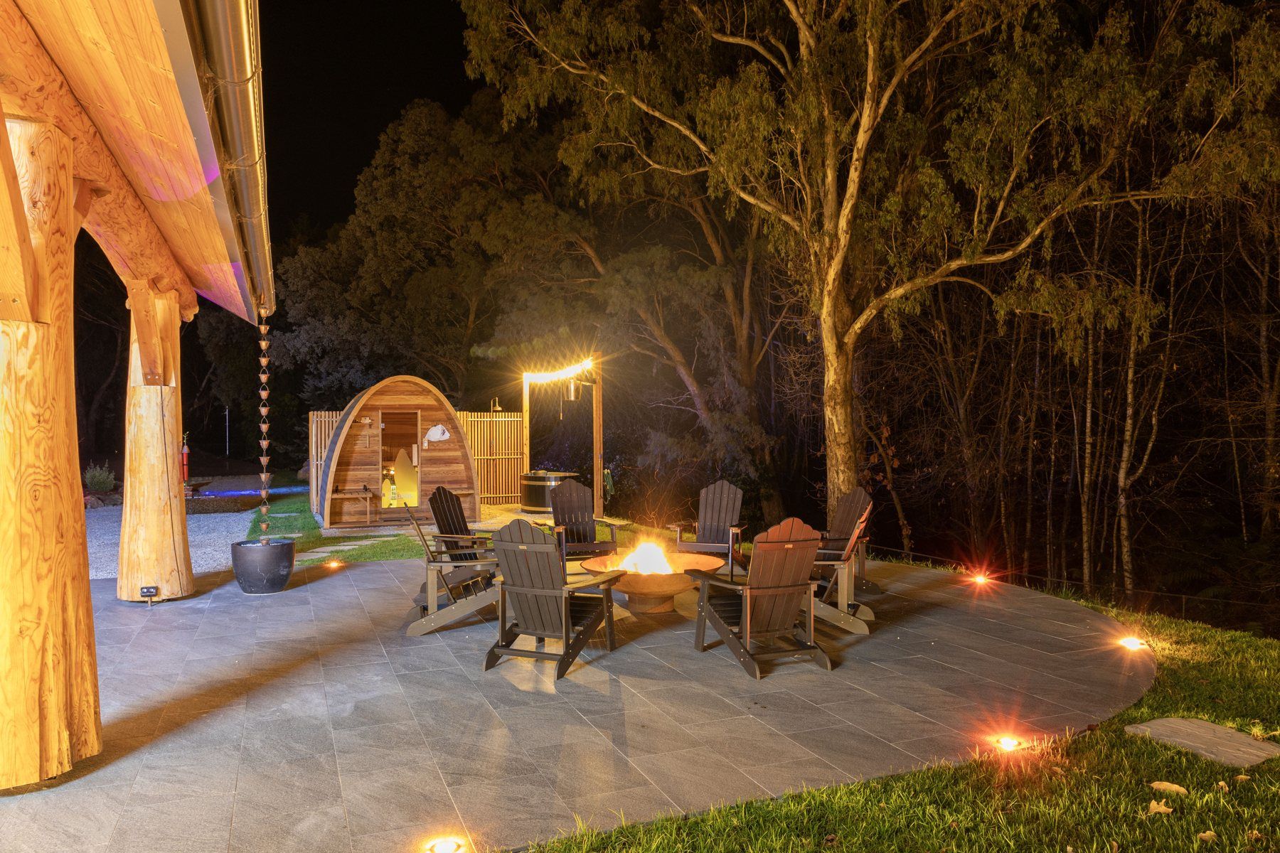 The firepit at night, chairs in a circle under the trees