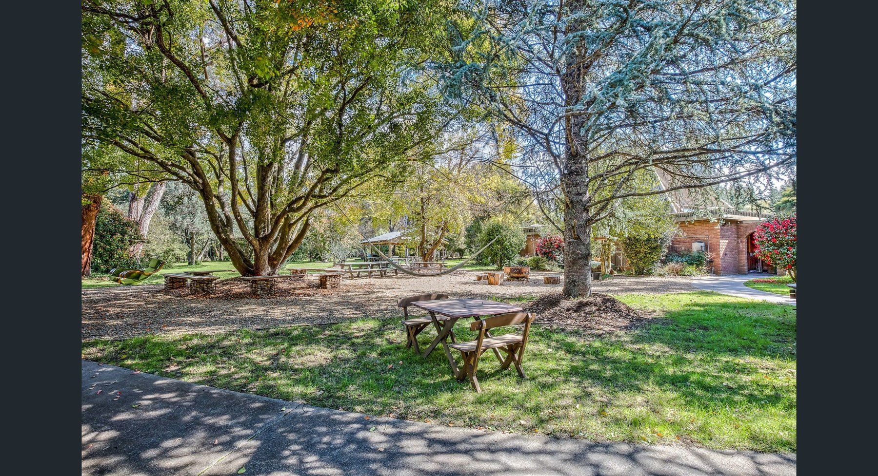 The camping lawn under old trees, a picnic table in the shade