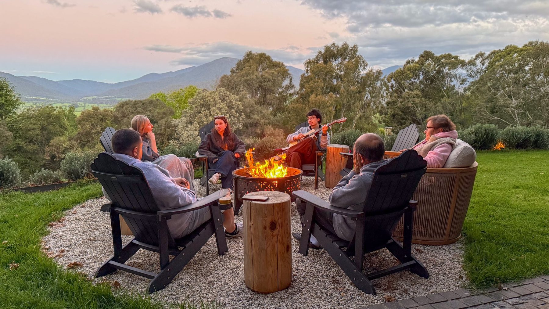 A group around the firepit at dusk, the ranges behind