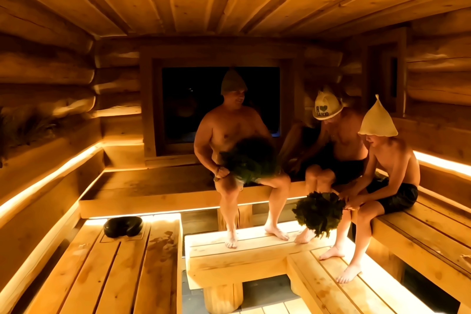 Friends on the benches of the Log Banya sauna, Mount Beauty, felt sauna hats on and oak whisks in hand